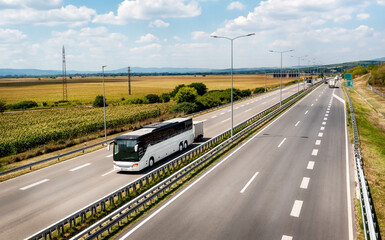 White Modern comfortable tourist bus driving through highway at bright sunny sunset. Travel and coach tourism concept. Trip and journey by vehicle