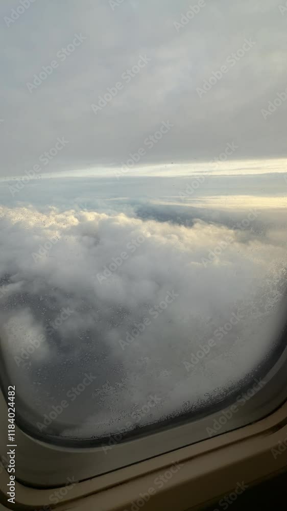 Poster view from airplane window showing clouds and sky during flight at high altitude