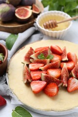 Making galette. Fresh dough, strawberries, figs and mint on table, closeup