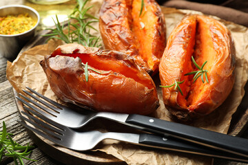Tasty cooked sweet potatoes served with rosemary on table, closeup