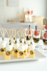 Many different tasty canapes on white table indoors
