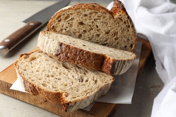 Cut loaf of fresh bread and knife on table, closeup