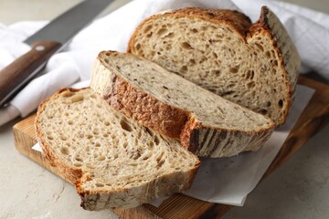 Cut loaf of fresh bread and knife on table, closeup
