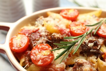 Delicious pasta casserole with cheese, tomatoes, minced meat and rosemary in baking dish, closeup