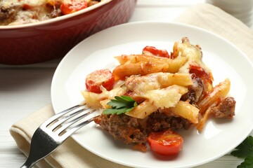 Delicious pasta casserole with cheese, tomatoes, minced meat and parsley on white wooden table, closeup