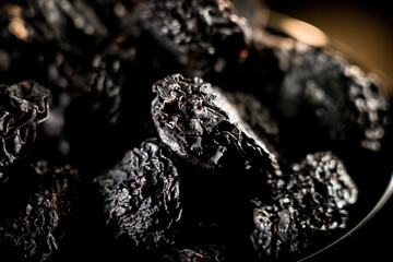 Dried prunes resting on a plate showcasing rich texture against a dark background