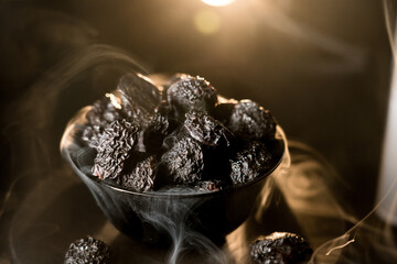 Close-up view of dried prunes on a black plate highlighting unique texture against a dark background