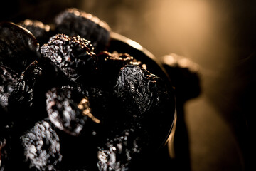 Close-up view of dried prunes highlighting rich texture against a dark background with soft lighting