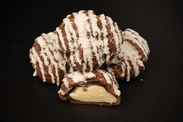 Profiteroles with coconut cream on a black background.