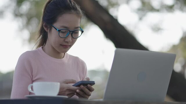A woman is using a smartphone amd working in the garden.