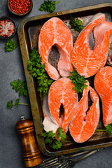 Fresh raw salmon steaks on a metal tray, ready to be cooked. Top view. Vertical photo.