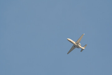 A small plane is flying in the sky. The sky is clear and blue. The plane is low to the ground