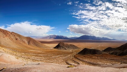 Naklejka premium Vast desert landscape with mountains under a bright blue sky and scattered clouds. Nature and wilderness concept