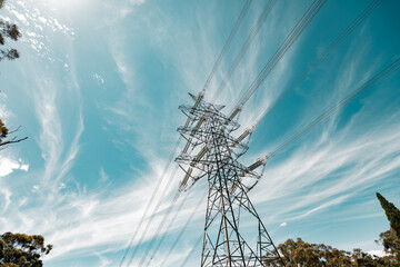 Electricity pylon with dramatic clouds and blue sky, symbolizing power and energy.