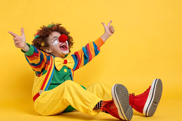 Funny kid clown playing against yellow background
