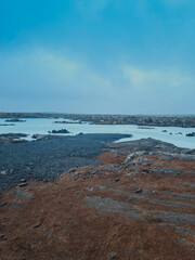 A stunning view of the Blue Lagoon in Iceland, showcasing its iconic milky blue geothermal waters surrounded by rugged volcanic rocks. The misty atmosphere 