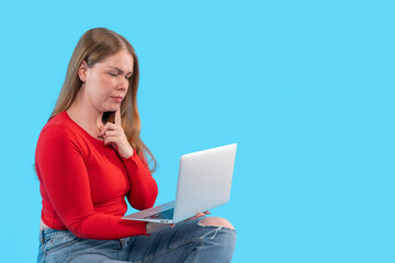 Young woman sitting on floor with laptop while deep in thought during creative brainstorming