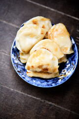 Dumplings with potato and cottage cheese stuffing (pierogi). Wooden background. Copy space.
