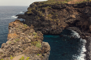 View of a blue ocean and rocky cliff with green patches, Tenerife