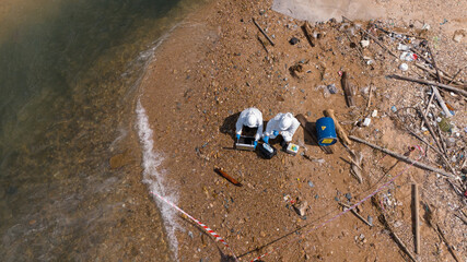 A male and female biologist are analyzing water test results and collecting samples for examination.