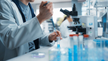 Medical Research Laboratory: Scientist Using Micropipette to Analyze Samples Under Microscope....