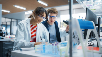 Molecular Biology Students Conducting Research in a Lab, Looking at DNA Sample Under a Microscope...
