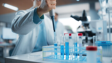 Medical Research Laboratory: Scientist Using Micropipette to Analyze Samples Under Microscope....
