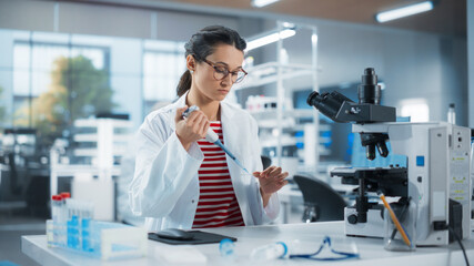 Medical Research Laboratory: Portrait of a Beautiful Scientist Using Micropipette to Analyze...