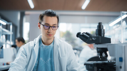 Genetic Research and Development Laboratory: Portrait of a Young Science Student Working and Looking at a Sample Under a Microscope. Advanced Biotechnology Lab with Modern Equipment