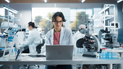 Portrait of a Smart Female Student Working on Laptop on a Research Project in School. Medical...