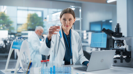 Caucasian Female Medical Research Scientist Work on a New Generation Medical Products in a Modern Laboratory. Young Woman Working on a Laptop Computer, Browsing Research Data Online