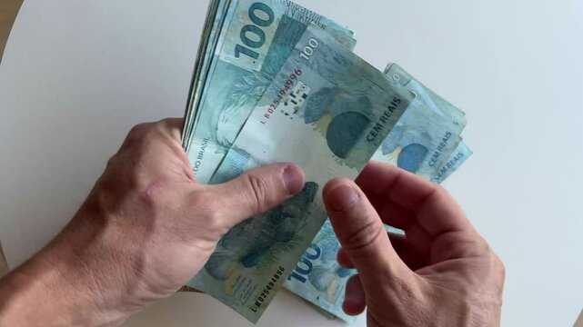 m&atilde;os contando notas de dinheiro real 