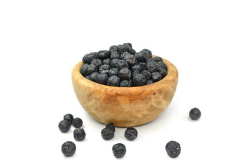 Aronia berries in a wooden bowl isolated against white background. Black chokeberry or aronia berries, isolated on white background, can be used to make wine, jam, syrup, juice, soft spreads,
