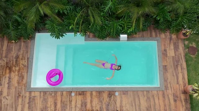 mulher relaxa na piscina no ver&atilde;o 