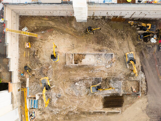 Aerial image above an excavated construction site with several machines in excavated pit