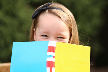 Happy little girl peeking out from behind book