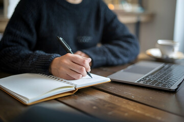 Writing notebook near laptop thoughtful focus on planning or journaling