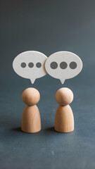 Wooden figurines with speech bubbles suggest dialogue on muted blue gray background Vertical Mobile Wallpaper
