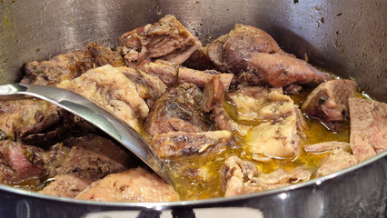 Turkey meat being stewed in a pot over an induction stove, with a spoon used to stir the dish. A hearty and flavorful meal prepared for a homemade family lunch or dinner.
