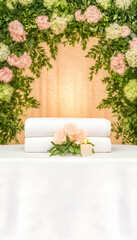 Spa treatment setup with towels, roses, and candle under floral arch.  Perfect for wellness brochures