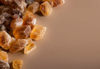 Detailed close-up of caramel-colored rock sugar crystals with a smooth beige background. Perfect for culinary, food, or texture-based design projects.