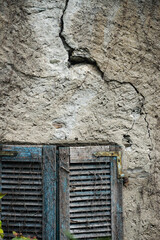 Weathered window shutters on a cracked wall in Vogogna