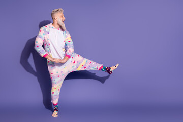 Joyful man in unicorn pajamas posing playfully against a purple background, radiating happiness