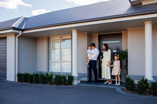 Portrait of family of four standing together outside home dad mum and two children