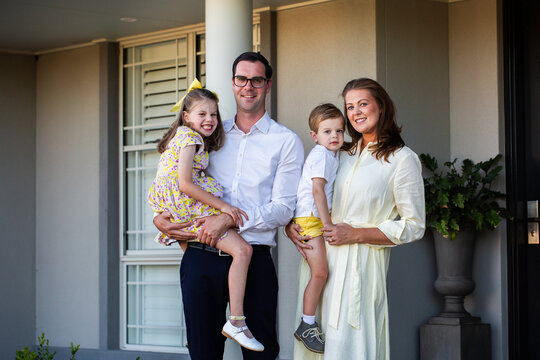 Portrait of family of four standing together outside home dad mum and two children