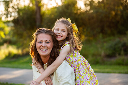 Joyful portrait of happy smiling mother and young daughter in golden light outdoors