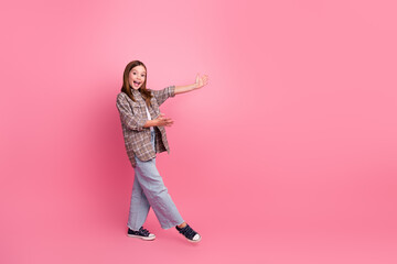 Smiling girl showcasing in trendy outfit on pink backdrop, expressing joy and casual style.