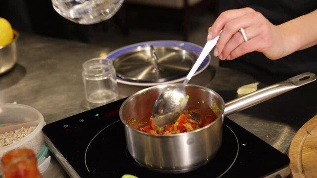 Water jug, Tomato pouring, Induction sauce. Water is being poured from jug into pan vegetable tomato sauce on induction stovetop.