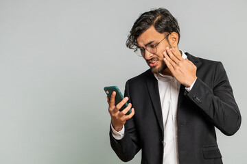 Upset sad Indian businessman use smartphone typing browsing, play game, loses, surprised by sudden...