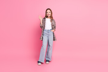 Full-length portrait of a cute young girl posing cheerfully against a pink backdrop